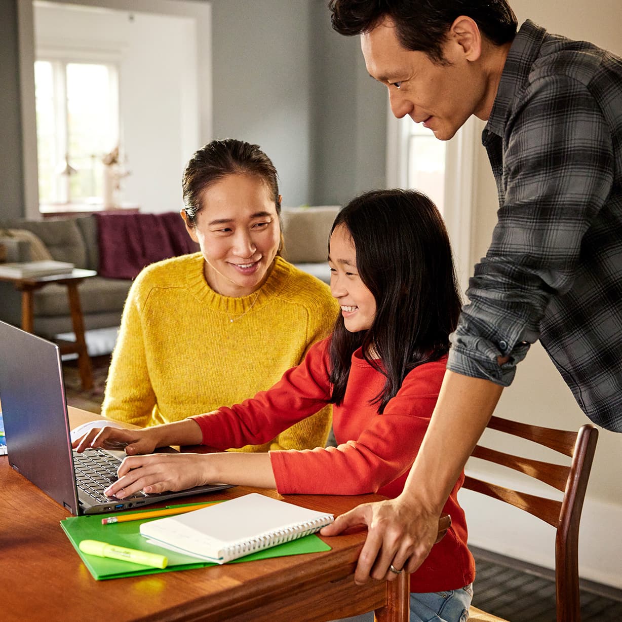 A child sits at a desk typing on a Chromebook with two adults on each side. Three Family Link graphics are next to the image.